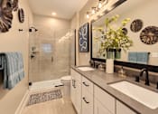 Thumbnail 5 of 29 - A bathroom with a sink, mirror, and shower.
