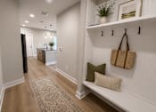 Thumbnail 1 of 11 - A hallway with a bench and a rug on the floor.