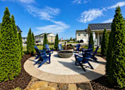 Thumbnail 57 of 65 - A circular patio with blue chairs and a fire pit in the middle.