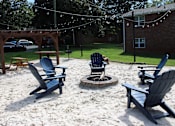 Thumbnail 18 of 24 - A sandy area with chairs and a fire pit.