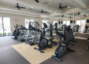 Thumbnail 17 of 30 - a gym with various exercise machines and ceiling fans