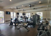 Thumbnail 18 of 30 - a gym with cardio equipment and ceiling fans