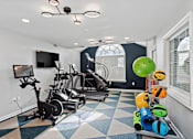 Thumbnail 2 of 13 - A room with a treadmill, exercise bike, and a television.