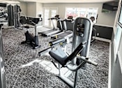 Thumbnail 22 of 30 - A gym with a variety of equipment including treadmills, weights, and exercise machines.
