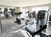 Thumbnail 23 of 30 - A gym with a variety of equipment including treadmills, weights, and exercise machines.