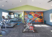 Thumbnail 3 of 18 - a gym with cardio machines and a colorful mural on the wall