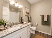 Thumbnail 23 of 25 - A bathroom with a white toilet, sink, and a mirror.