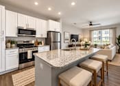 Thumbnail 1 of 25 - A kitchen with a granite countertop and white cabinets.