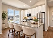 Thumbnail 6 of 25 - A kitchen with a granite countertop and bar stools.