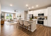 Thumbnail 4 of 25 - A modern kitchen with a dining area and a ceiling fan.