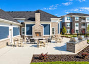 Thumbnail 9 of 25 - A patio with a fireplace and chairs is surrounded by a brick wall.