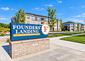 Thumbnail 8 of 25 - A sign for Founders Landing Apartments in front of a building.