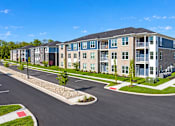 Thumbnail 24 of 25 - A large apartment complex with a parking lot in front.