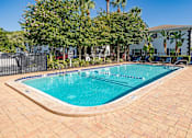 Thumbnail 2 of 10 - A small pool surrounded by a brick patio and trees.
