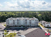 Thumbnail 20 of 23 - A large white building with a parking lot in front of it.