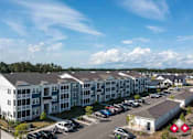 Thumbnail 21 of 23 - A large apartment complex with multiple buildings and a parking lot in front.