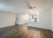 Thumbnail 9 of 35 - A spacious room with a ceiling fan and wooden flooring.