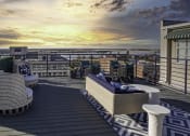 Thumbnail 3 of 7 - a rooftop deck with furniture and a sunset over the ocean