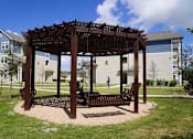 Thumbnail 29 of 29 - a bench under a wooden pavilion in a park