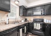 Thumbnail 3 of 23 - A black kitchen with granite countertops and a black oven.