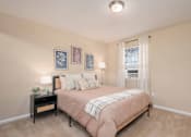 Thumbnail 10 of 23 - A bedroom with a bed, nightstand, and pictures on the wall.