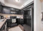 Thumbnail 4 of 23 - A black fridge in a kitchen with black cabinets.