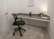 Thumbnail 17 of 43 - A black office chair is in front of a desk with a plant and a picture on the wall.