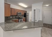 Thumbnail 18 of 43 - A kitchen with granite countertops and white walls.