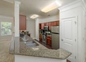 Thumbnail 7 of 43 - A kitchen with brown cabinets and a granite countertop.