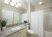 Thumbnail 27 of 32 - A bathroom with a white toilet, sink, and shower curtain.