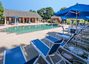 Thumbnail 46 of 67 - A pool area with sun loungers and a building in the background.