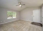 Thumbnail 12 of 23 - A room with a ceiling fan and a door leading to another room.