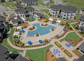 Thumbnail 1 of 58 - A large swimming pool surrounded by blue lounge chairs and umbrellas is the centerpiece of a resort-style community.