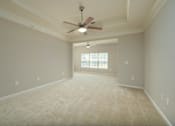 Thumbnail 16 of 48 - A room with a ceiling fan and carpeted floor.
