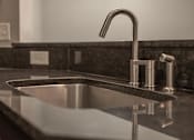 Thumbnail 13 of 48 - A modern sink with a chrome faucet and a dark granite countertop.