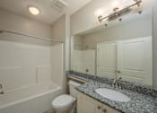 Thumbnail 33 of 48 - A bathroom with a granite countertop and white fixtures.