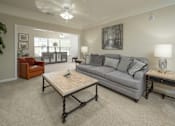 Thumbnail 22 of 37 - A living room with a grey couch, a wooden coffee table, and a ceiling fan.