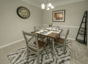 Thumbnail 25 of 37 - A dining room with a table set for two and a clock on the wall.