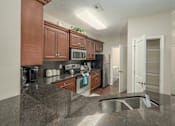 Thumbnail 34 of 37 - A kitchen with brown cabinets and a black refrigerator.
