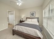 Thumbnail 27 of 37 - A bedroom with a bed, nightstand, and window with blinds.