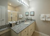 Thumbnail 29 of 37 - A bathroom with a granite counter top and a mirror.