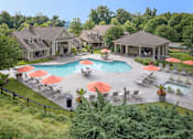 Thumbnail 4 of 37 - A large outdoor swimming pool surrounded by red umbrellas and lounge chairs.