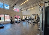 Thumbnail 21 of 33 - A gym with a variety of equipment including treadmills, weights, and exercise machines.