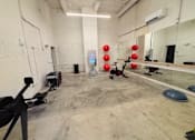 Thumbnail 23 of 33 - A gym with a mirror, weights, and exercise equipment.