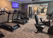 Thumbnail 26 of 26 - A gym with treadmills and a television.
