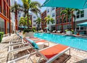 Thumbnail 20 of 25 - A pool with sun loungers and umbrellas in front of a building.