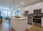 Thumbnail 4 of 25 - A modern kitchen with white cabinets and stainless steel appliances.
