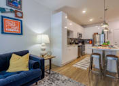 Thumbnail 6 of 25 - A blue couch with a yellow pillow sits in a living room.
