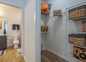 Thumbnail 11 of 25 - A bathroom with a toilet and a shelf with baskets on it.
