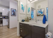 Thumbnail 9 of 25 - A bathroom with a sink, mirror, and two vases.
